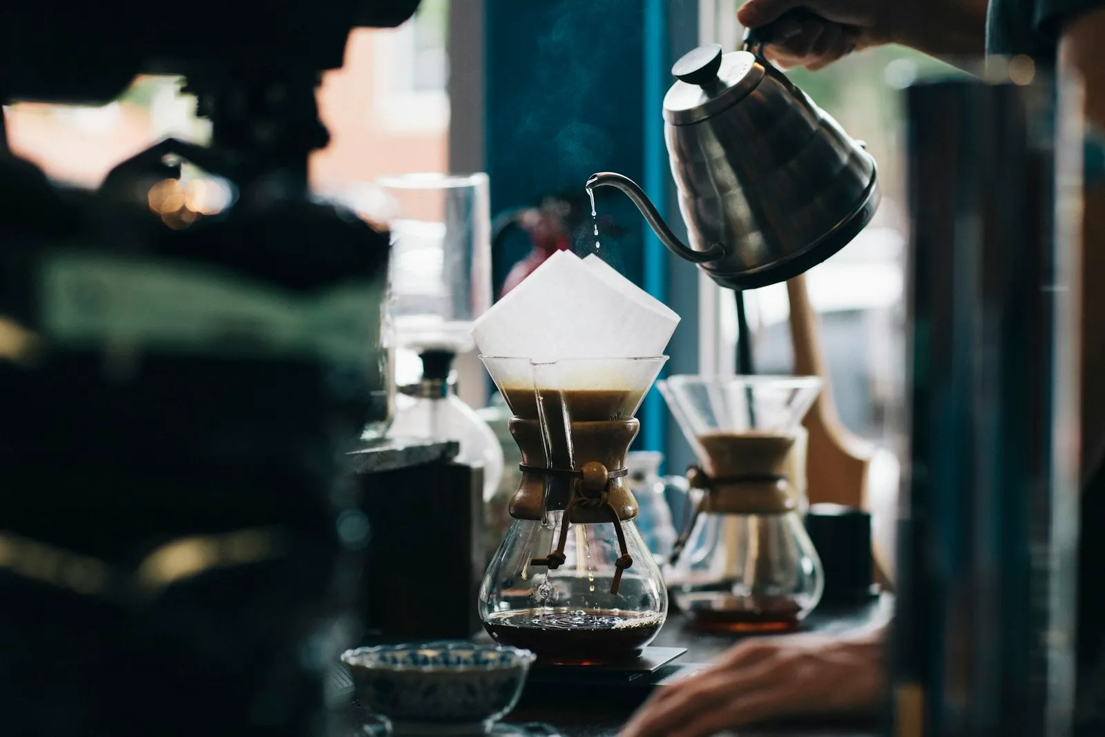 A barista slowly pouring water over a paper-filter coffee brewer
